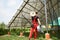 Guy standing under a solar station on a green part near the house with a coil of wires on his shoulder and in his hands