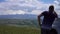 Guy stands near the SUV with a view of the mountains and the forest