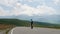 Guy in summer in black clothes descends from the mountain on a skateboard