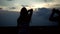 A guy takes photos of his girlfriend on the roof at night. Beautiful silhouettes against the sky