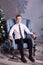 Guy teenager in trousers and a shirt with a tie sitting on an armchair near a Christmas tree in the New Year