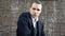 A guy with a terrible look in a 1920s suit waving his hat standing on the background of the old wall, close up shooting