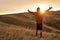 guy on top of mountain reaches for the sun during sunrise, feel happiness, enjoy the morning