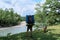 Guy is traveler and tourist. Young handsome Caucasian man with German shepherd is walking along bank of mountain river with large