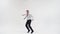 A guy in trousers and a shirt is dancing the bottom break with his feet, Bouncing his legs apart, holding one hand on