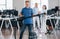 Guy with vacuum cleaner. Group of workers clean modern office together at daytime