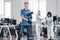 Guy with vacuum cleaner. Group of workers clean modern office together at daytime