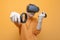 Guy in VR glasses on an orange background, a gamer holds joysticks and plays a virtual shooter