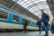 A guy waiting for the train at the Prague main train station with people boarding the blue train of Ceske Drahy