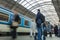 A guy waiting for the train at the Prague main train station with people boarding the blue train of Ceske Drahy