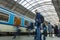 A guy waiting for the train at the Prague main train station with people boarding the blue train of Ceske Drahy