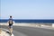 The guy walks along the road against the backdrop of the Mediterranean Sea in calm.