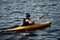 A guy wearing a helmet on a canoe polo rowing a paddle and sailing on water. canupolo. puts on a rescue yellow. rear view. water