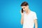 A guy in a white T-shirt talking on the phone on a blue isolated background, talkative young man