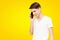 The guy in the white T-shirt talking on the phone on a yellow isolated background, talkative young man