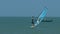 Guy windsurfer sails past fishing boat at ocean
