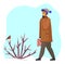 Guy in winter clothes walking near snow-covered bush with bullfinch, man looking at bird on branch