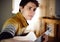 Guy in yellow sweater plays acoustic guitar while sitting at home