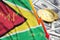 Guyana flag and cryptocurrency falling trend with two bitcoins on dollar bills
