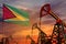 Guyana oil industry concept. Industrial illustration - Guyana flag and oil wells with the red and blue sunset or sunrise sky
