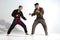 Guys in kimono fighting during karate workout on white studio backdrop with copy space, martial arts concept