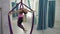 In gym beautiful athletic woman does exercises on aerial silk.