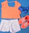 Gym clothes for fitness strength training workout layed out on blue exercise mat top view. Orange matching t-shirt and shoes,