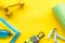 Gym equipment - dumbbells, jump rope - frame on yellow background top-down copy space