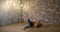 Gymnast is training alone and stretching body in fitness room in evening time, sitting on floor