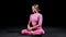 Gymnastics - young woman in pink costume sits down in lotus pose