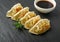Gyoza Chinese Dumplings, Fried Vegetable Jiaozi, Chicken Momo Pile, Asian Gyoza Group on Black Stone Plate