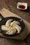 Gyozas, fried japanese dumplings on cast-iron pan served with soy sauce.
