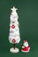 Gypsum colorful santa claus and christmas tree with decorations over green background. New Year and Christmas concept.