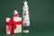 Gypsum colorful santa claus on the gift box and christmas tree with decorations over green background. Copy space