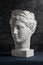 Gypsum copy of ancient statue Diana head on a dark textured background. Plaster sculpture woman face.