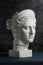 Gypsum copy of ancient statue Diana head on a dark textured background. Plaster sculpture woman face.