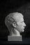 Gypsum copy of ancient statue Germanicus head on dark textured background. Plaster sculpture man face.