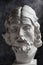 Gypsum copy of ancient statue John the Baptist head on dark textured background. Plaster sculpture man face.