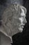 Gypsum copy of ancient statue Seneca head on dark textured background. Plaster sculpture man face.