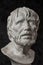 Gypsum copy of ancient statue Seneca head on dark textured background. Plaster sculpture man face.