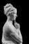 Gypsum copy of ancient statue of thinking young lady isolated on black background. Side view of plaster sculpture woman