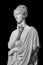 Gypsum copy of ancient statue of thinking young lady isolated on black background. Side view of plaster sculpture woman