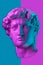 Gypsum copy of head statue David in bright neon colors for artists on a color background. Face famous sculpture youth of