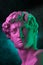 Gypsum copy of head statue David in bright neon colors for artists on a dark background. Face famous sculpture youth of