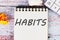 HABITS word written on a sheet of notebook lying on old vintage boards with a calculator and folded paper