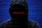 Hacker attack concept. Unrecognizable faceless mysterious male hacker in black hoodie poses against dark background, tries to brea