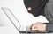 Hacker in balaclava writing virus code on laptop keyboard