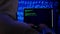Hacker in dark room writing programming code or using virus program for cyber attack.