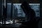 Hacker dressed in a hoodie, sitting in a dark room surrounded by monitors, coding malicious software. Ai generated