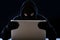 Hacker man in black hood and mask with computer laptop hacking system in digital intruder cyber crime concept